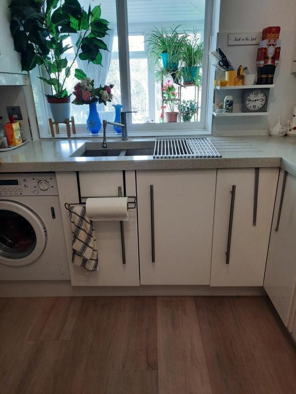 a kitchen with a sink and a washing machine at Comfortable quiet room near Cambridge in Long Stanton