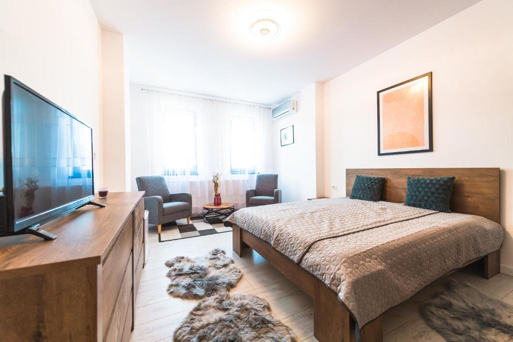a bedroom with a large bed and a flat screen tv at EVRA APARTMENTS in Recaş