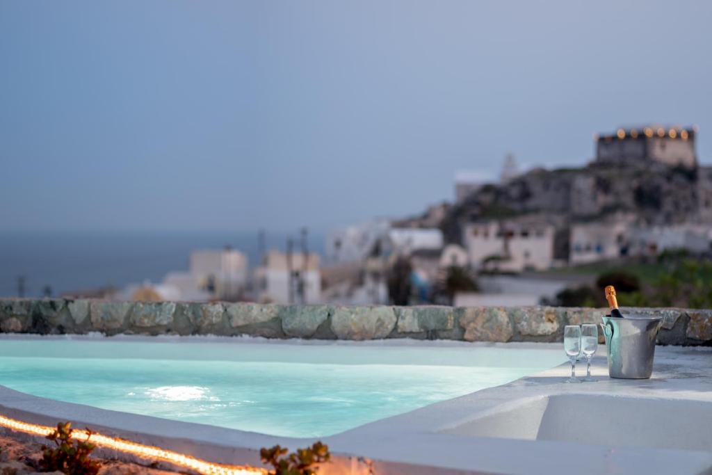 un tavolo con due bicchieri da vino accanto alla piscina di Red Cliff Santorini Villa - Volcano View & Jacuzzi ad Akrotírion