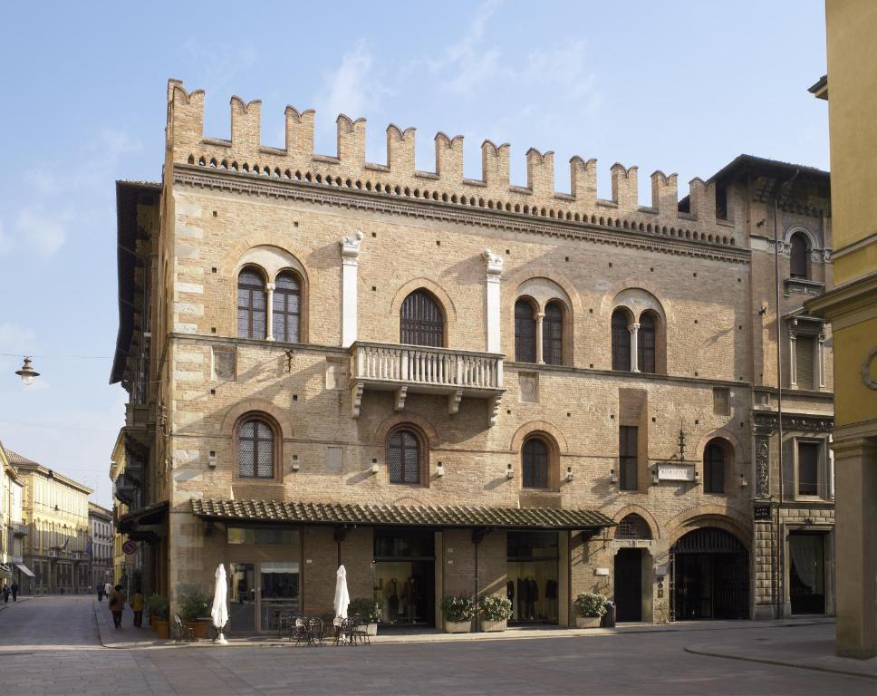 a large brick building with a balcony on a street at Hotel Posta in Reggio Emilia