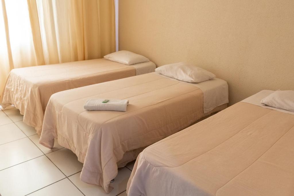 a room with three beds with towels on them at ALVORADA PALACE HOTEL in Bauru