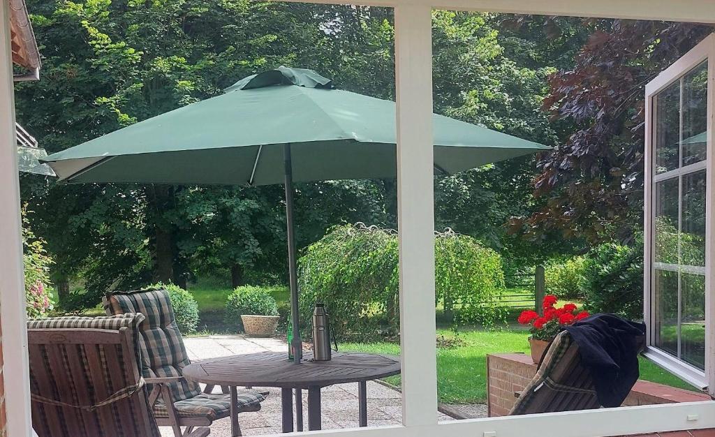 a table with a green umbrella on a patio at Ferienwohnung-Volker in Tönning