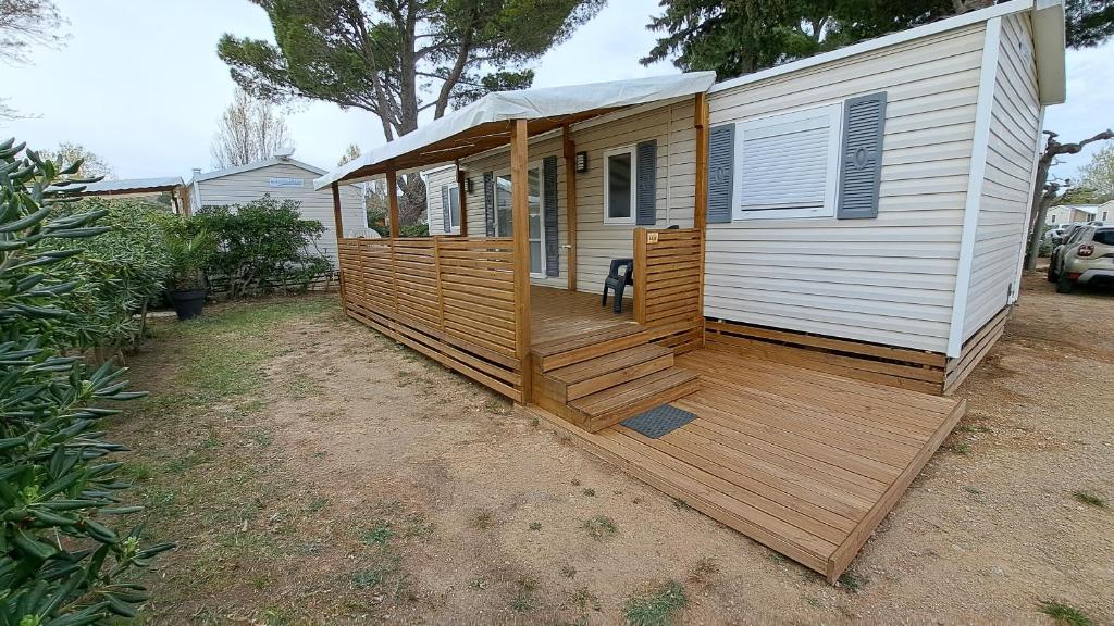 une cabine avec une terrasse en bois dans une cour dans l'établissement Mobile Home Climatisé 3 chambres à Narbonne Plage, à Narbonne-Plage