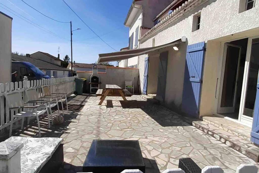 patio ze stołem piknikowym i ławkami obok budynku w obiekcie Maison de vacances 3 chambres avec terrasses w mieście Saint-Georges-de-Didonne