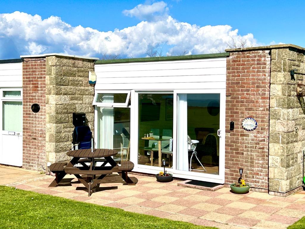 un edificio con una mesa de picnic delante de él en SEAVIEW self-catering coastal bungalow in rural West Wight en Freshwater
