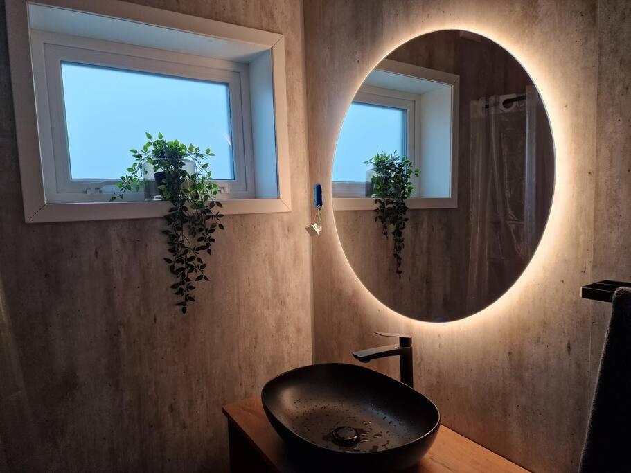 uma casa de banho com um espelho redondo e um lavatório em New flat with hot tub - No3 em Oyndarfjørður