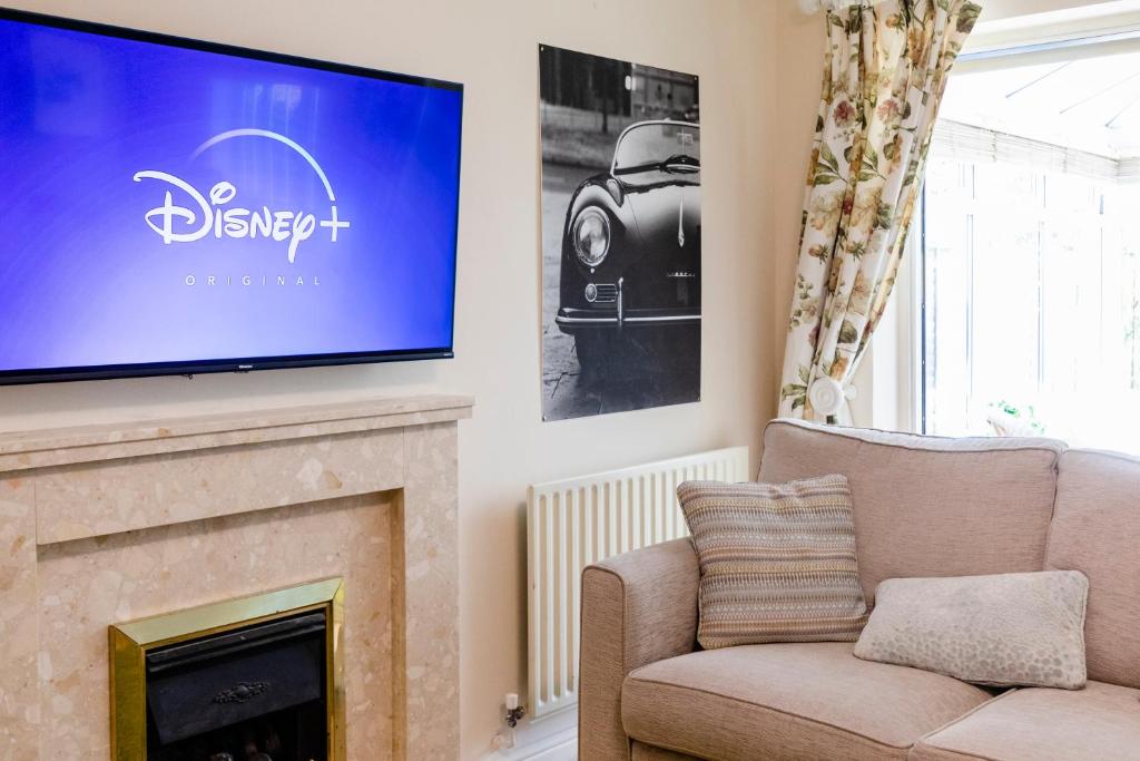 een woonkamer met een flatscreen-tv boven een open haard bij Chichester retreat house with free parking in Chichester