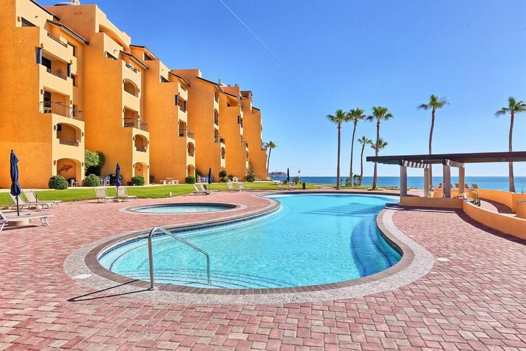 a swimming pool in front of a building at Sandy Beach Princesa D101 Ocean Front Resort in Puerto Peñasco