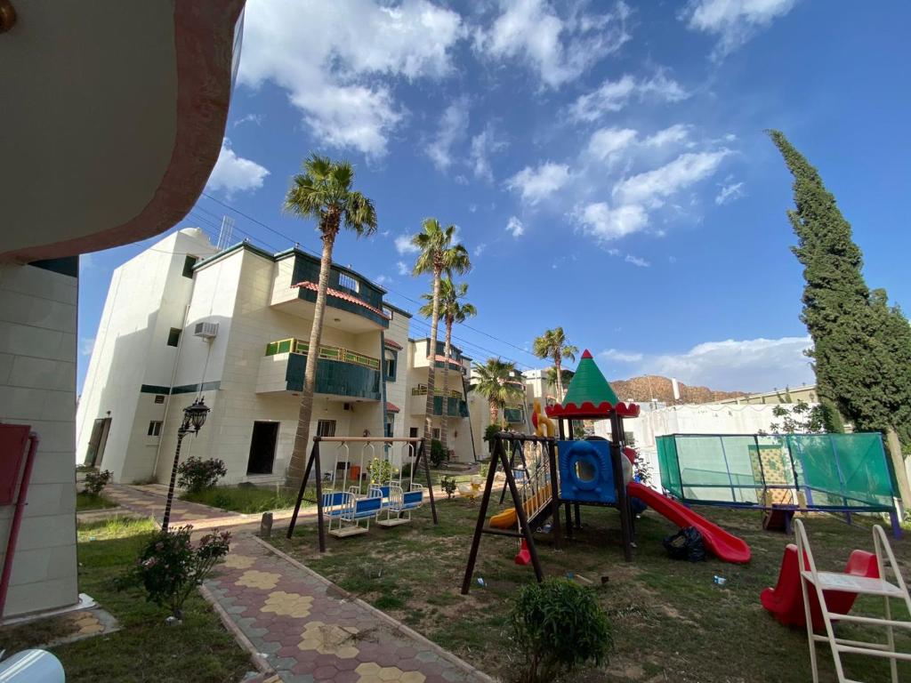 a playground in front of a house with palm trees at منتجع ليالي الحنين Layali Alhanin Resort in Al Hada