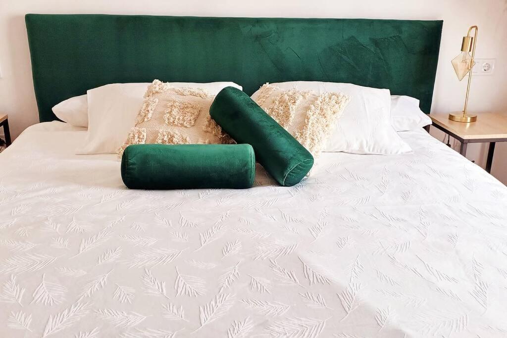 a white bed with two green pillows on it at Serendipia: tu hogar en este blanco pueblo in Frigiliana