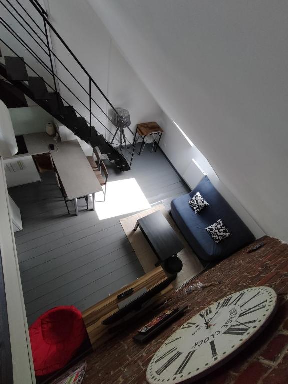 Cette chambre mansardée comprend un lit et un réveil. dans l'établissement Le Charmant, à Bohain-en-Vermandois