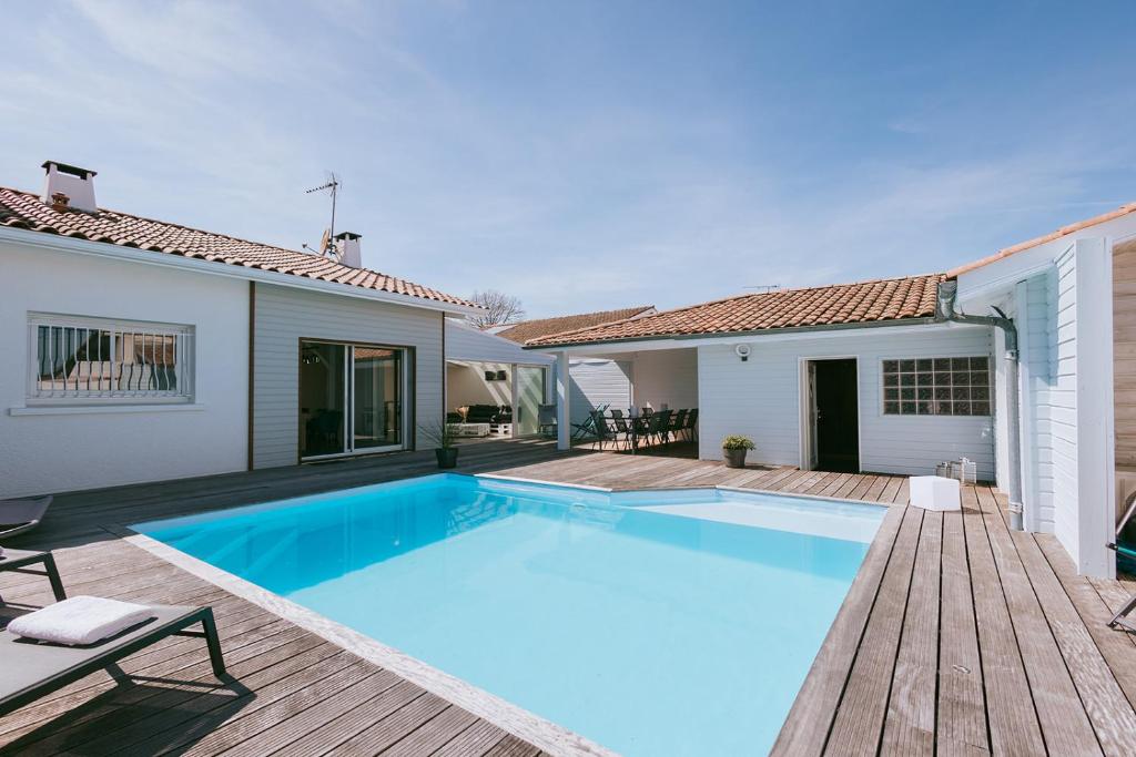 a swimming pool in a house with a wooden deck at Maison Le Basta in Bégaar