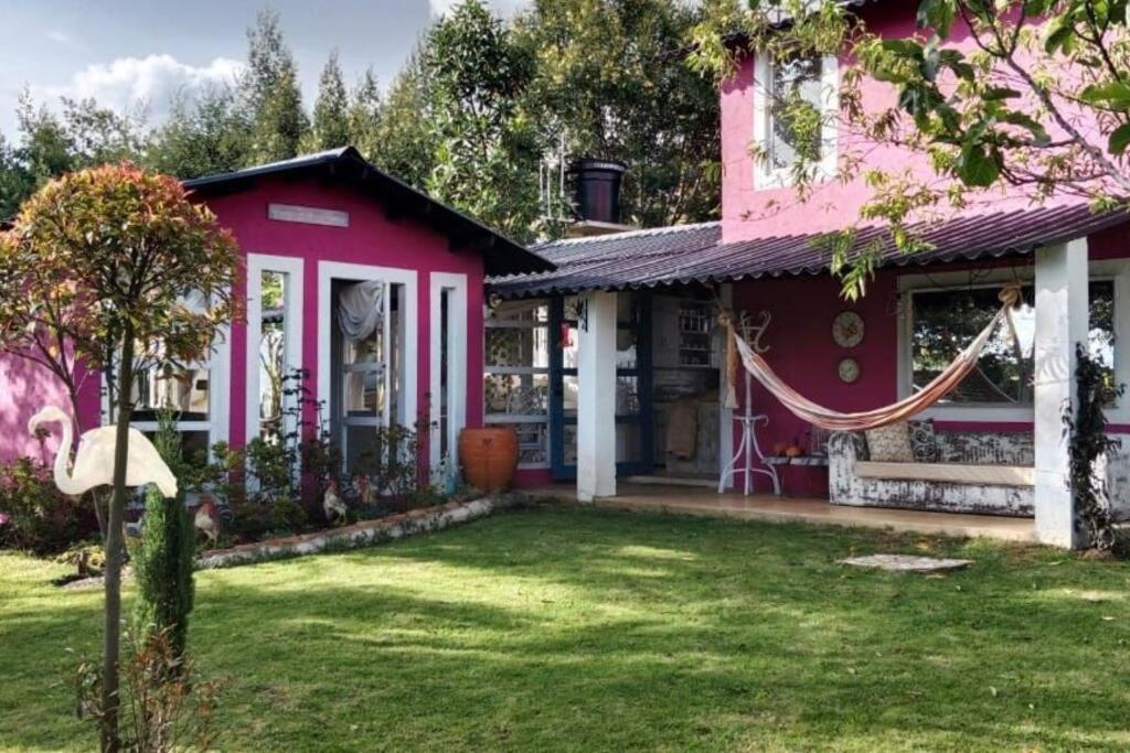 ein rosa Haus mit einer Hängematte im Hof in der Unterkunft Suite Campestre Flamingo Paipa Boyaca in Paipa