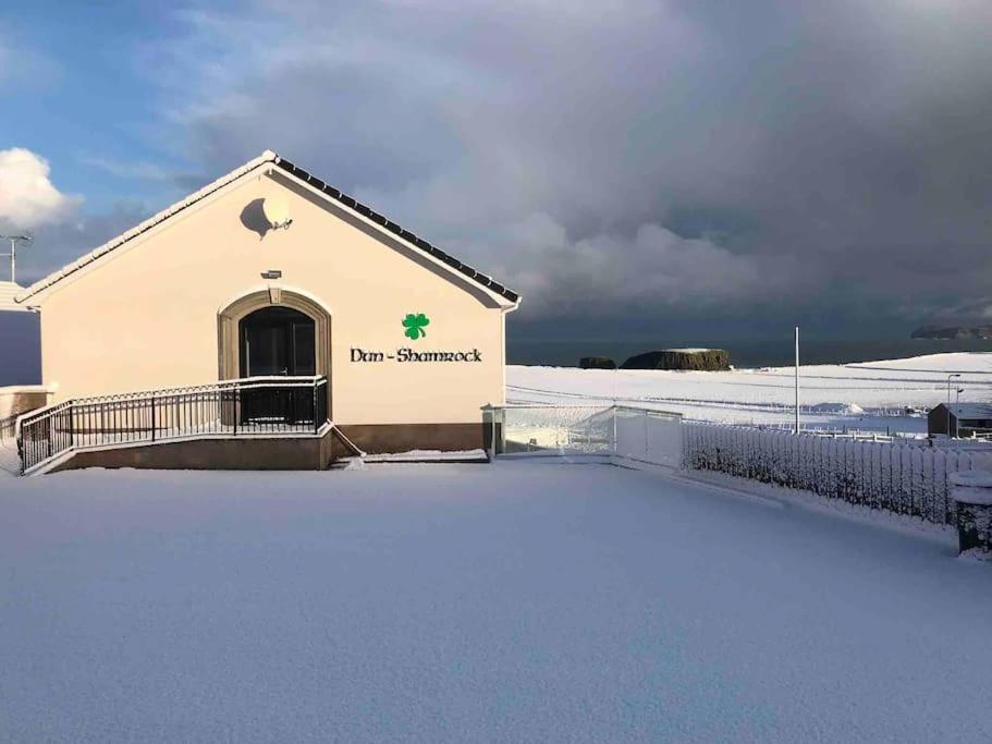 a building with snow on the ground in front of it at Dunshamrock @Sheep Island View in Ballintoy