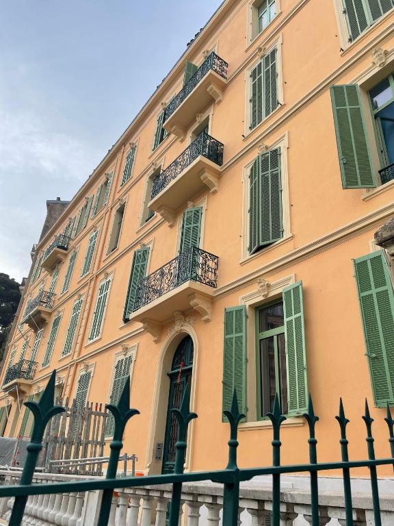 a yellow building with green shutters and a fence at Villa Corbelle - Grand Studio in Cannes