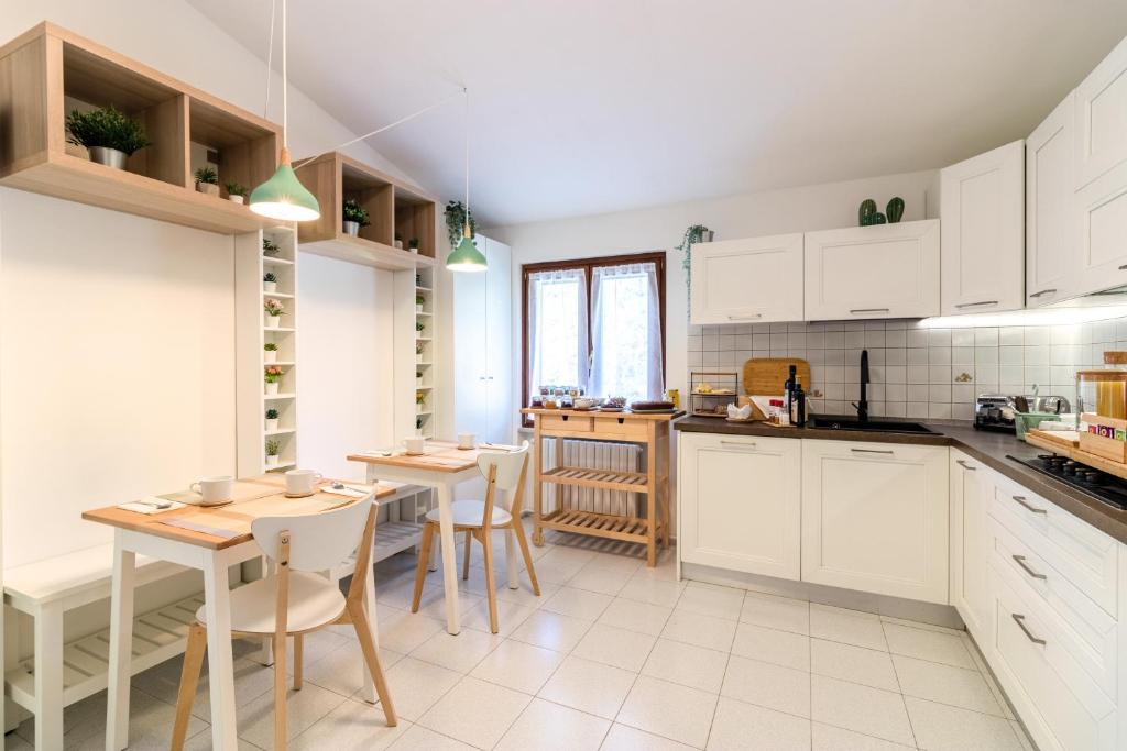 una cucina con armadi bianchi, tavolo e sedie di Maeva Guesthouse a Puegnago