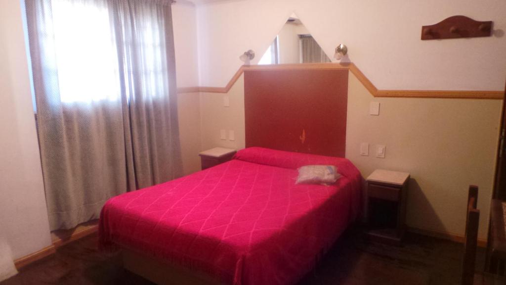 a bedroom with a pink bed and a staircase at Hotel Virreyes in San Fernando