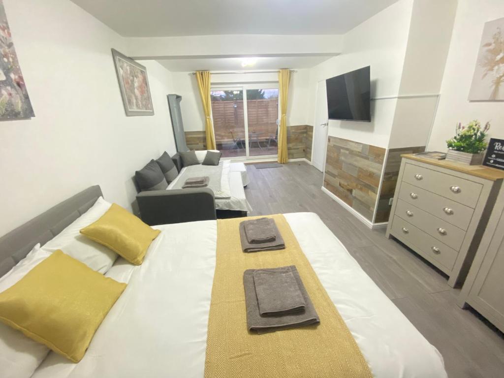 a bedroom with a bed and a couch and a television at Gatwick Studio in Horley