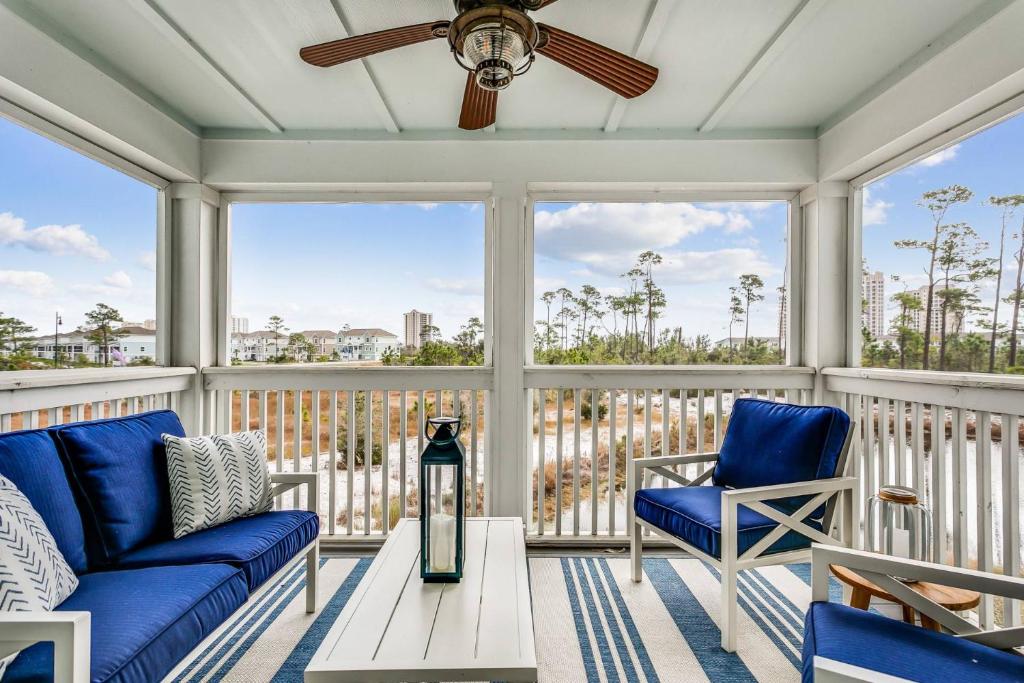 porche acristalado con sillas azules y ventilador de techo en Sandcastle by the Sea, en Pensacola