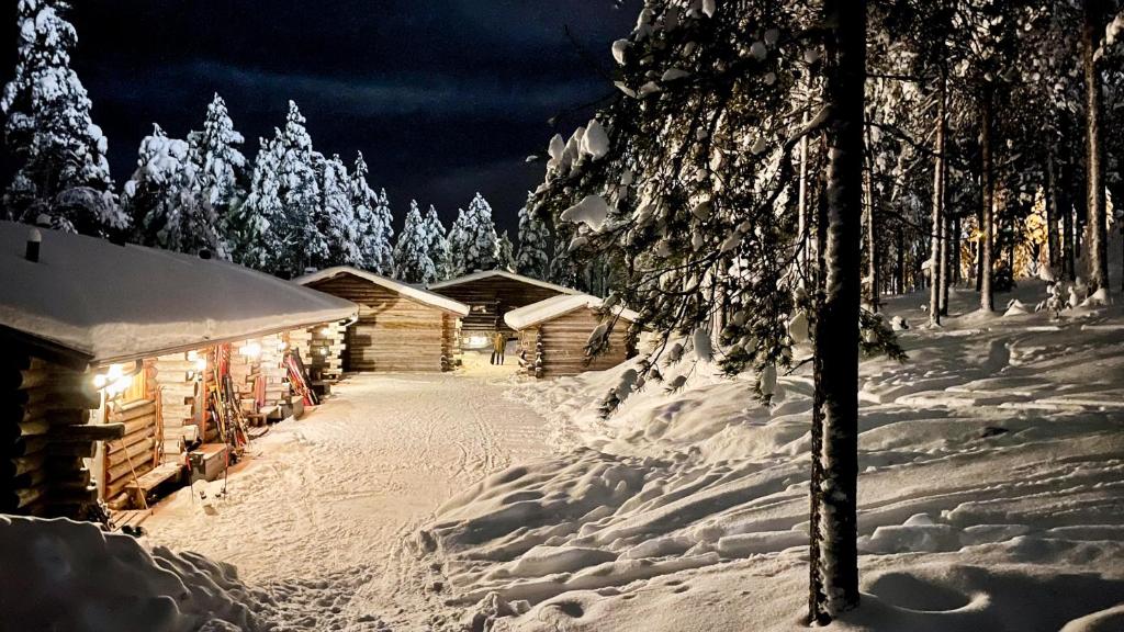 una baita di tronchi nella neve di notte di Ski-in-out FreeRider a Pyhätunturi