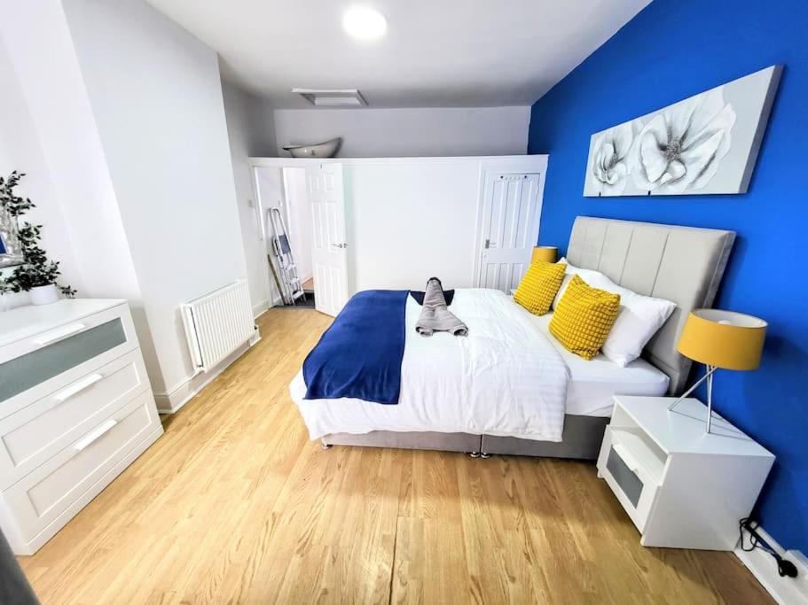 Un dormitorio con paredes azules y una cama blanca con almohadas amarillas. en Comfortable House near Etihad - Stay Sleep Rest en Mánchester