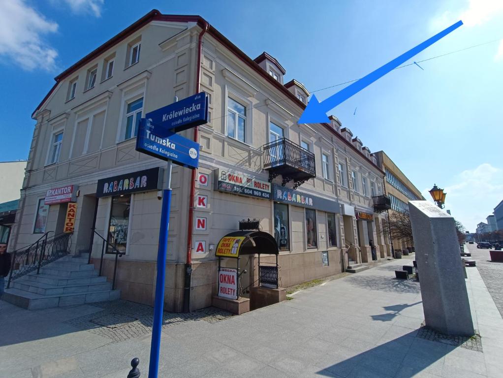 un pôle bleu avec des panneaux de rue devant un bâtiment dans l'établissement Green Apartment Tumska, à Płock