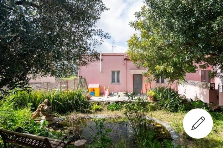 ein rosa Haus mit einem Teich im Hof in der Unterkunft Albero della musica in Sassari