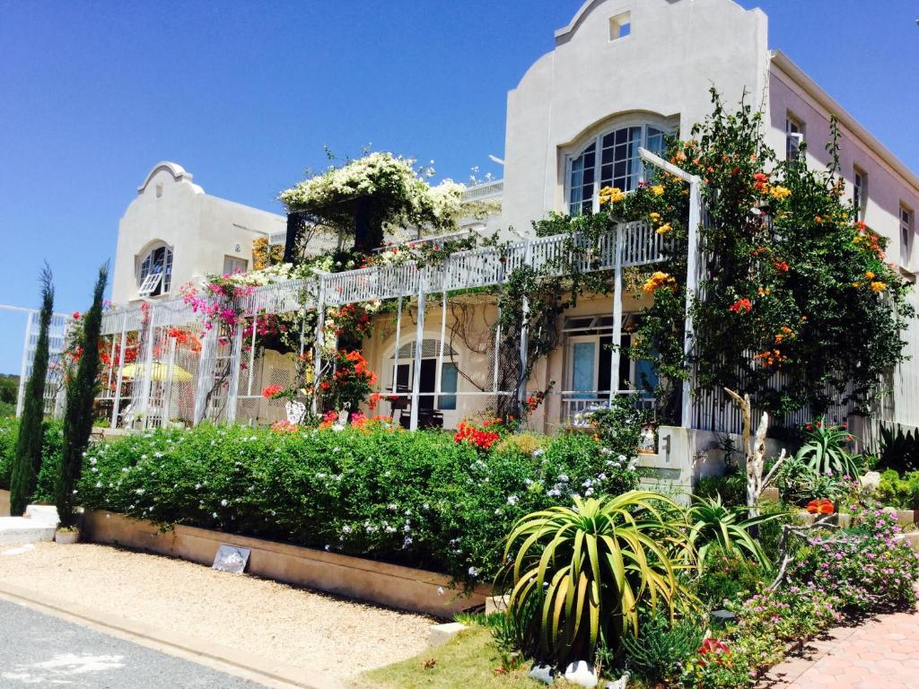 una casa con muchas flores delante de ella en Charlotte House, en Stilbaai