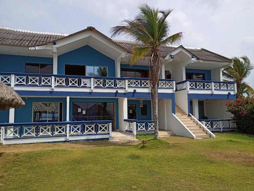 a blue house with a palm tree in front of it at Cabañas Cigua in Coveñas