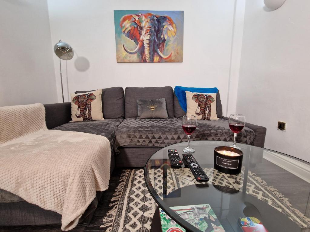 ein Wohnzimmer mit einem Sofa und 2 Gläsern Wein in der Unterkunft Spacious & comfy Home- very close to NEC Birmingham ,HS2 & Airport- Perfect for contractors & groups- free parking & Fast WiFi in Marston Green