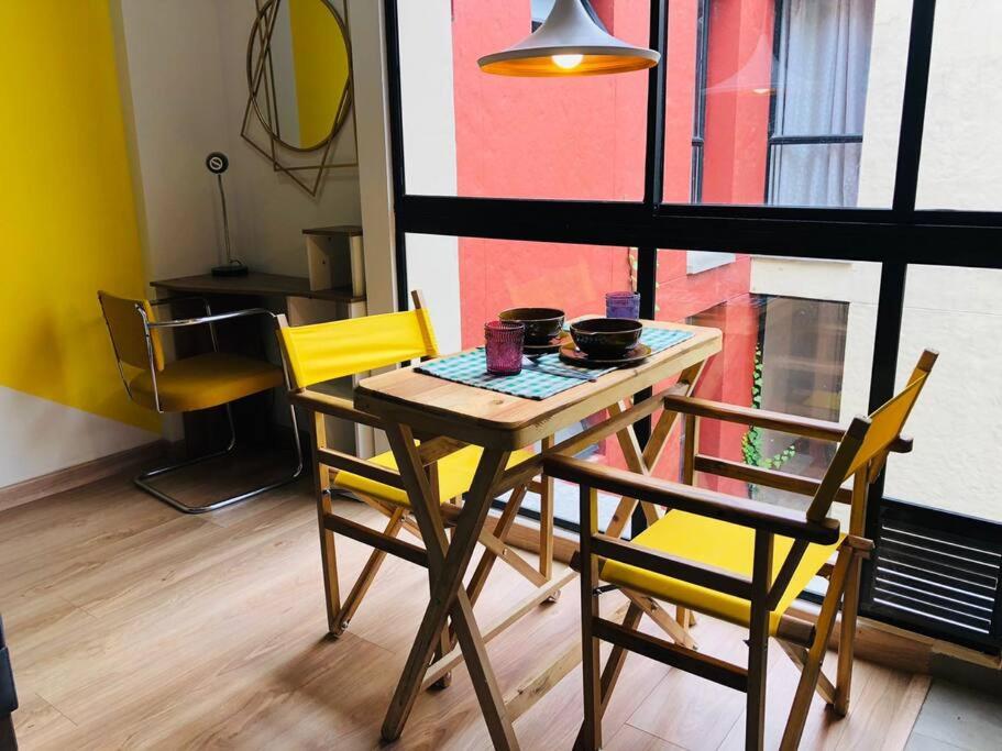 a dining room table with two chairs and a table with bowls on it at Hermoso loft en el centro histórico de Bogotá. in Bogotá