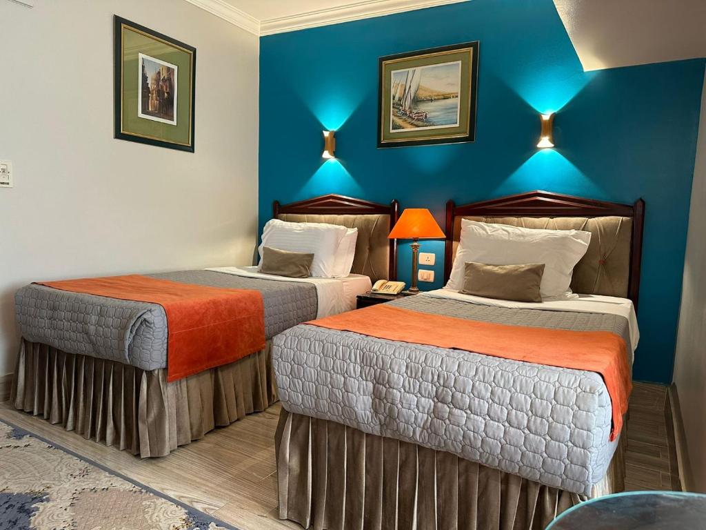 Gawharet Al Ahram Hotel في القاهرة: سريرين في غرفة بجدران زرقاء
