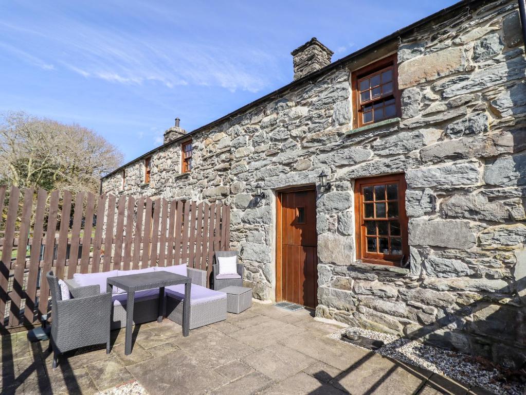 a stone house with a table and chairs in front of it at Cwm Yr Afon Cottage in Harlech