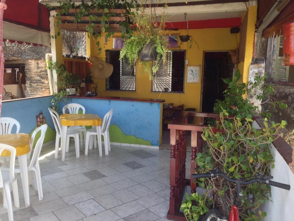 un restaurante con sillas blancas, mesa y sillas en Nega Maluca Guesthouse en Salvador