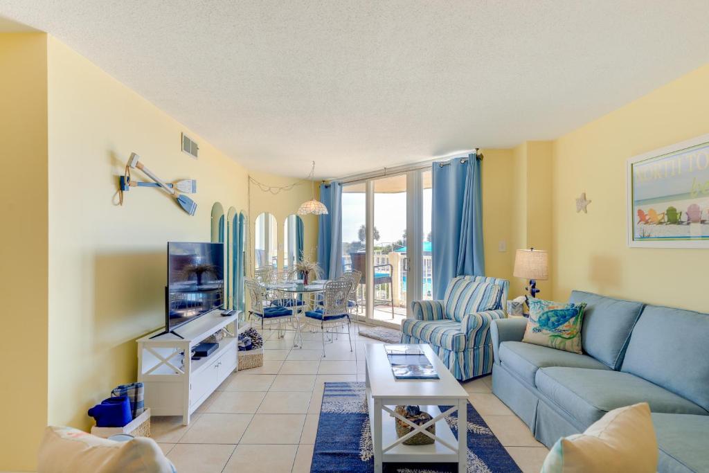 uma sala de estar com um sofá azul e uma televisão em North Carolina Escape with Balcony and Pool Access! em North Topsail Beach
