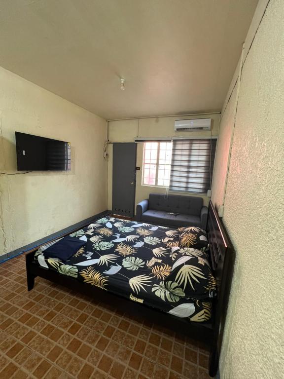 een slaapkamer met een bed en een bank erin bij Yna's Place - The Fourth House in Balintiouac
