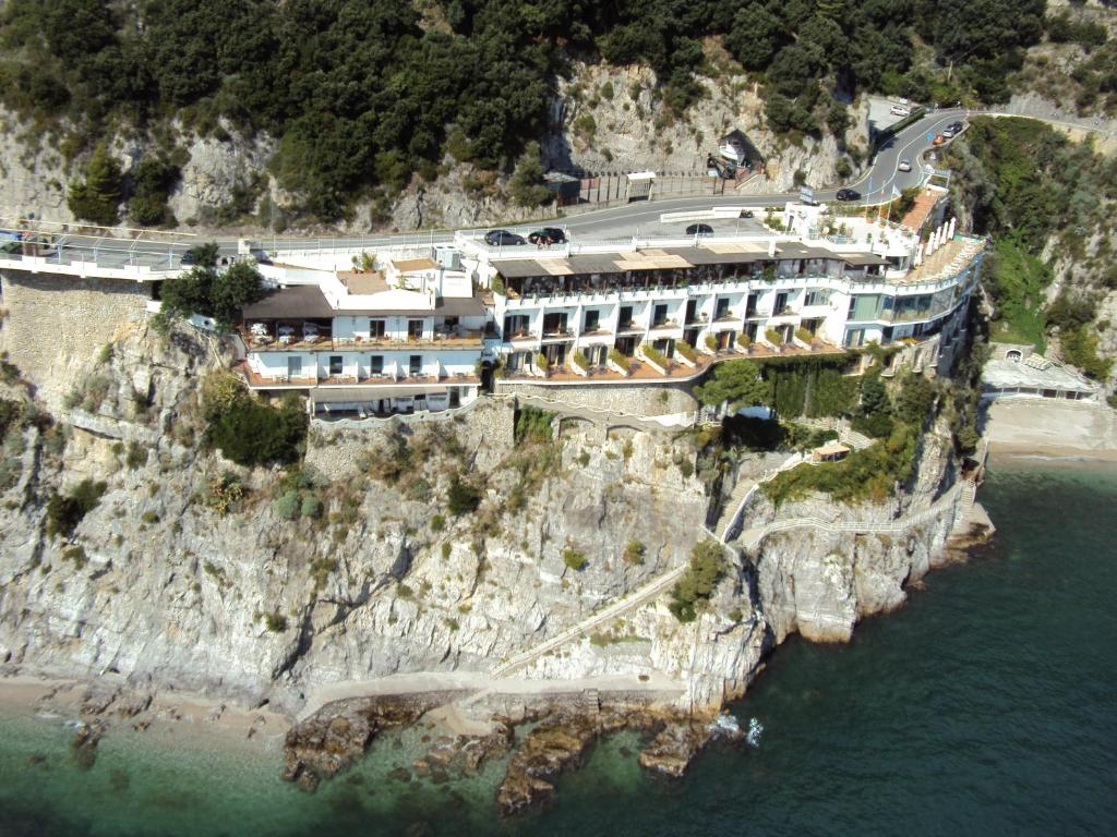 a building on the side of a cliff next to the water at Hotel Cetus in Cetara