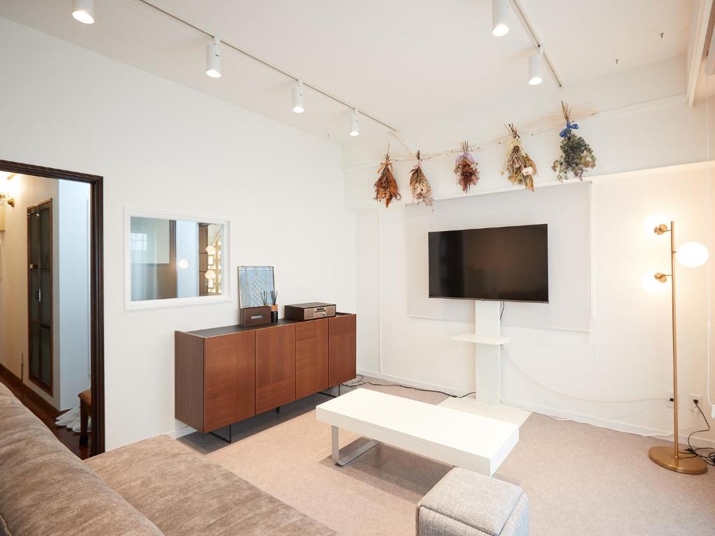 a living room with a couch and a flat screen tv at Guest house II Rokumarukan in Naha