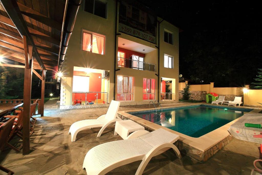 a swimming pool with white chairs and a building at DeluxeMaisonettes in Panoramic Roof Complex in Balchik