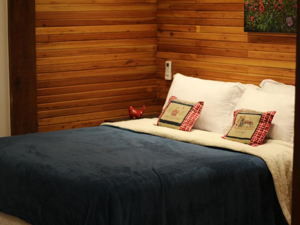 a bed with white pillows and a wooden wall at Fazenda Capuava in Bananal