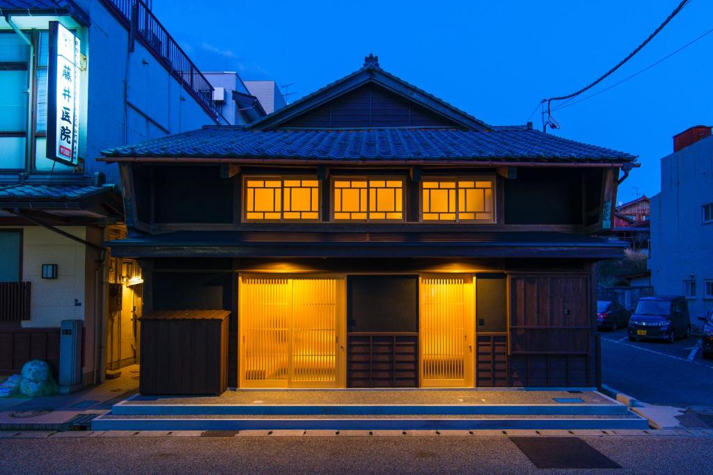 a house with lit windows on a street at Tsumesyo Mikuni in Sakai