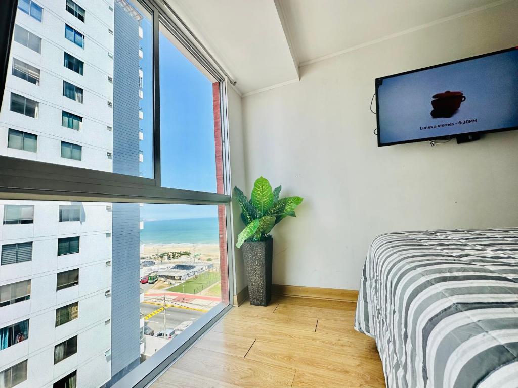 a bedroom with a large window and a tv at Casa Sol Apartamento vista al mar cerca del aeropuerto y Miraflores in Lima