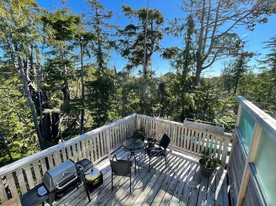 a deck with a table and chairs and trees at Brown's Beach Guest Suite in Ucluelet