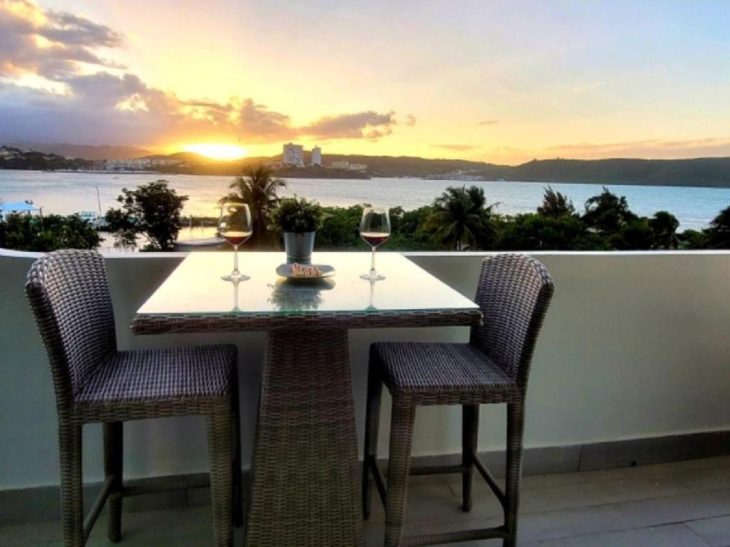 stół z dwoma kieliszkami wina na balkonie w obiekcie Ocean Zen w mieście Fajardo