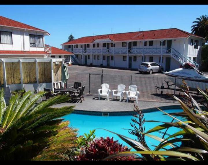 a hotel with a pool and chairs and a parking lot at Marlin Court Motel in Paihia
