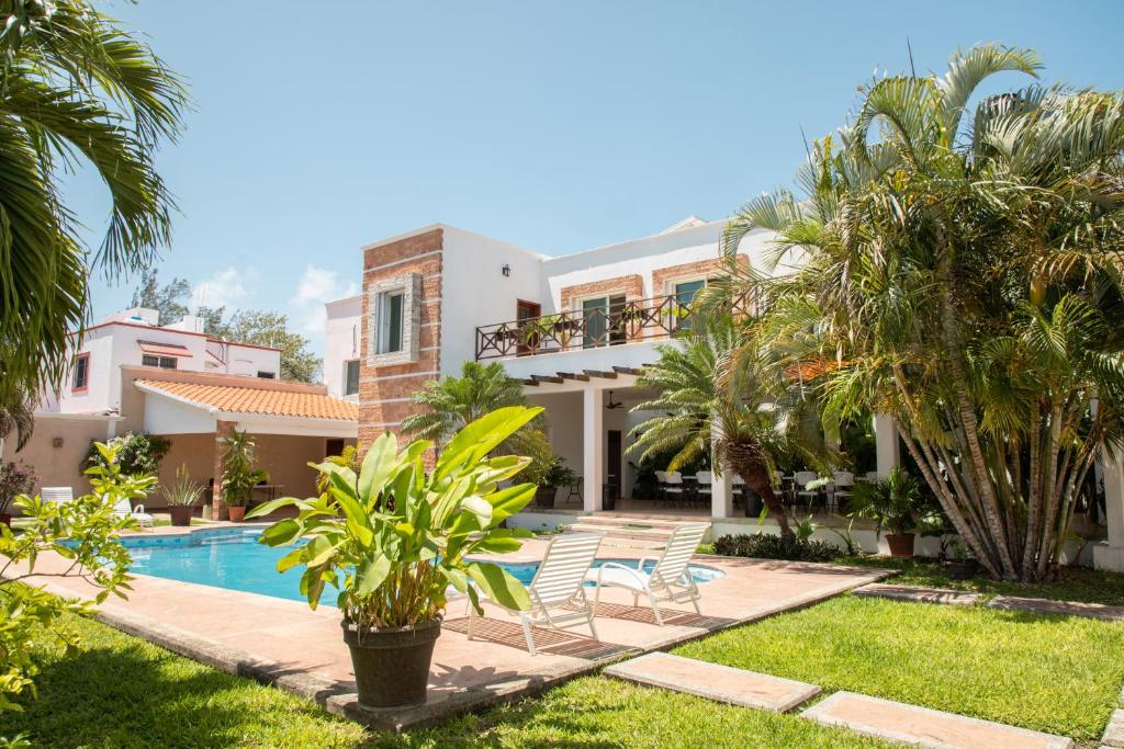 a villa with a swimming pool and palm trees at Departamento con alberca privada in Chetumal