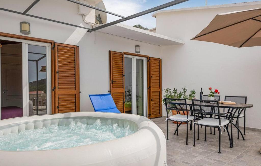 a hot tub in a patio with a table and chairs at Apartment Green Peace in Zadvarje