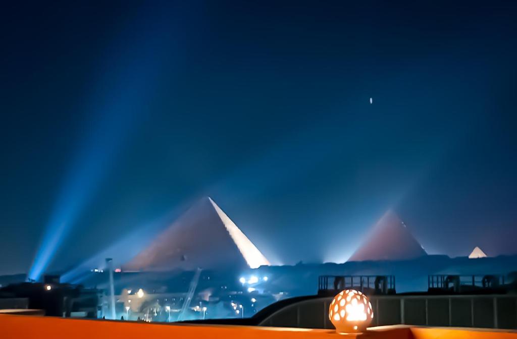 una vista de algunas pirámides por la noche con luces en Grand Pyramids In en Giza