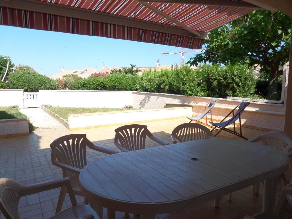 a wooden table and chairs on a patio with a table and chairs at Maison Palavas-les-Flots, 3 pièces, 7 personnes - FR-1-715-50 in Palavas-les-Flots
