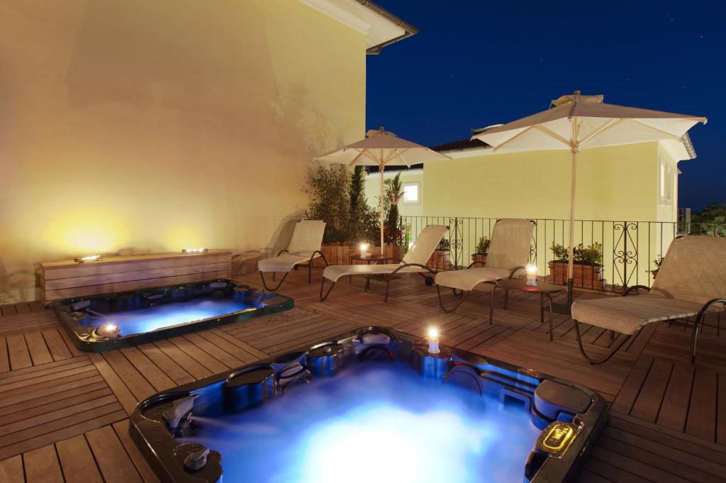 a hot tub on a deck with chairs and an umbrella at Hotel Corsignano in Pienza